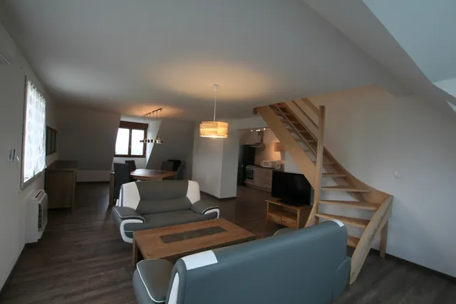 Séjour avec salon, coin repas et escalier vers les chambres